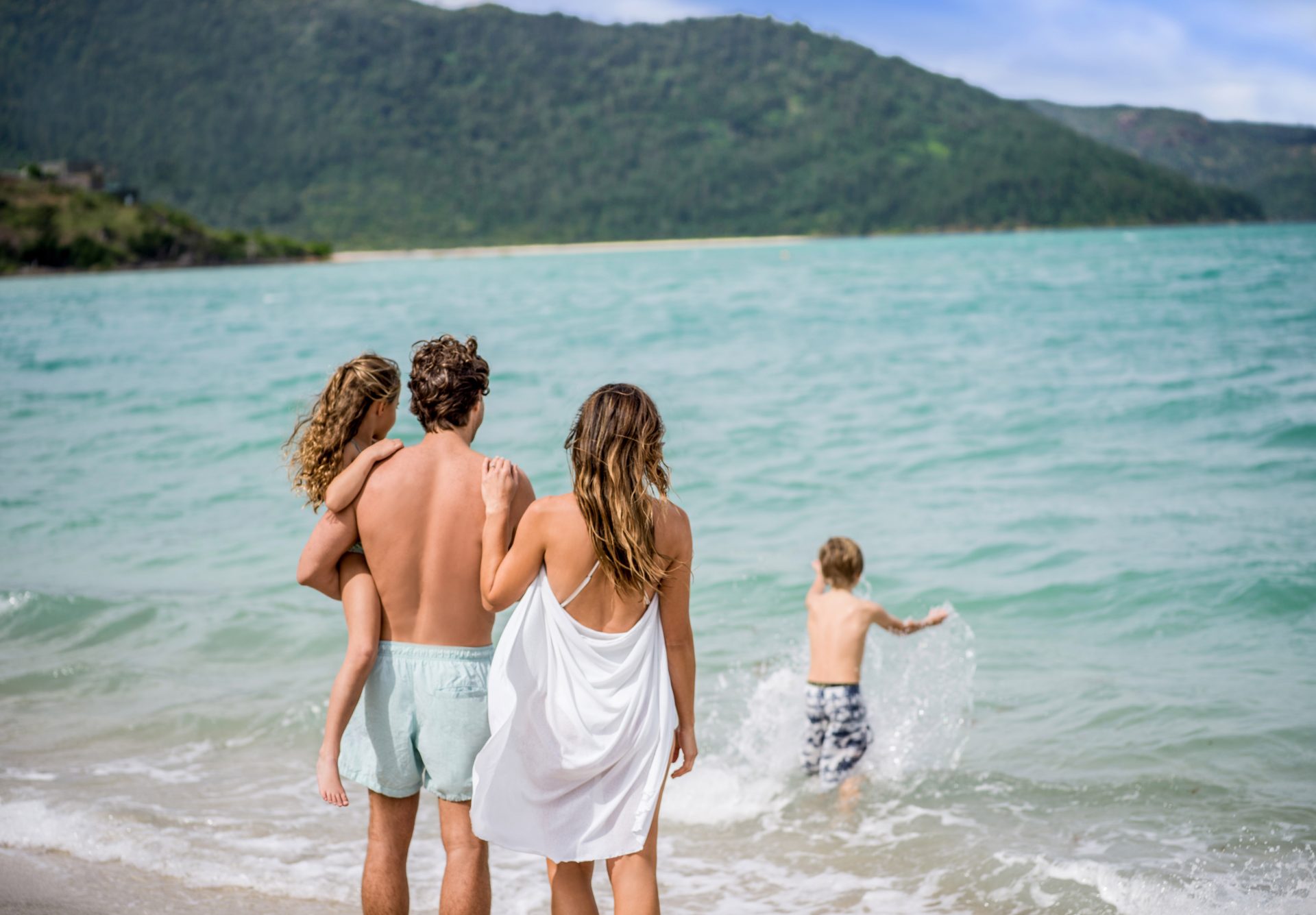 Family enjoying shallow turquoise water on a Whitsunday Island beach
