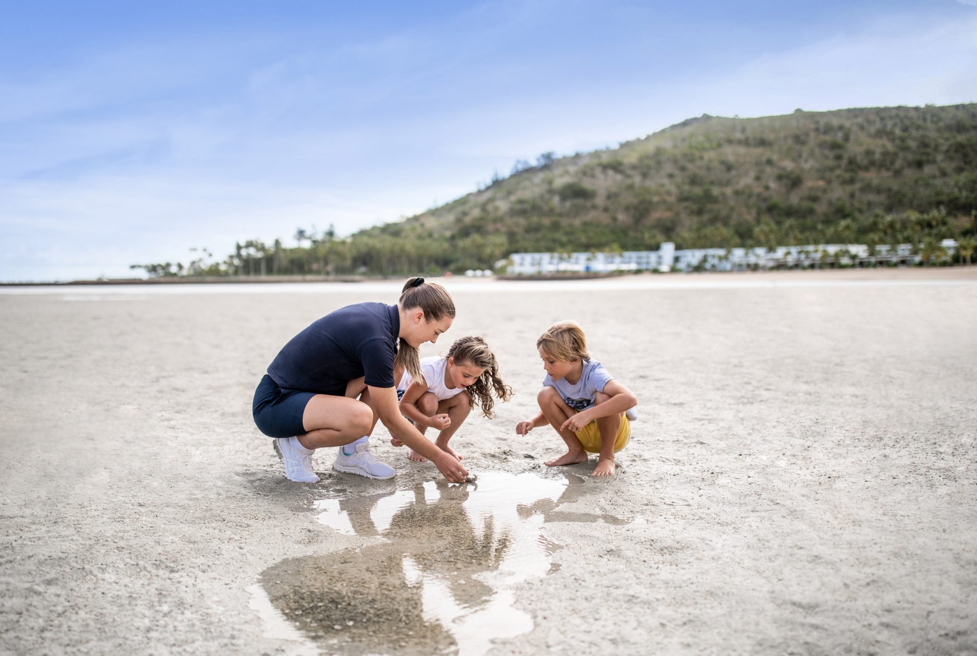 Family playing on white sand beach at a Whitsunday island resort