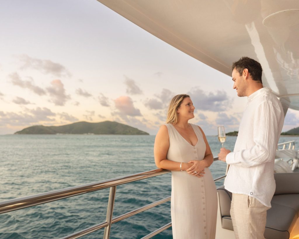 Couple toasting champagne on a private yacht in the Whitsundays at sunset