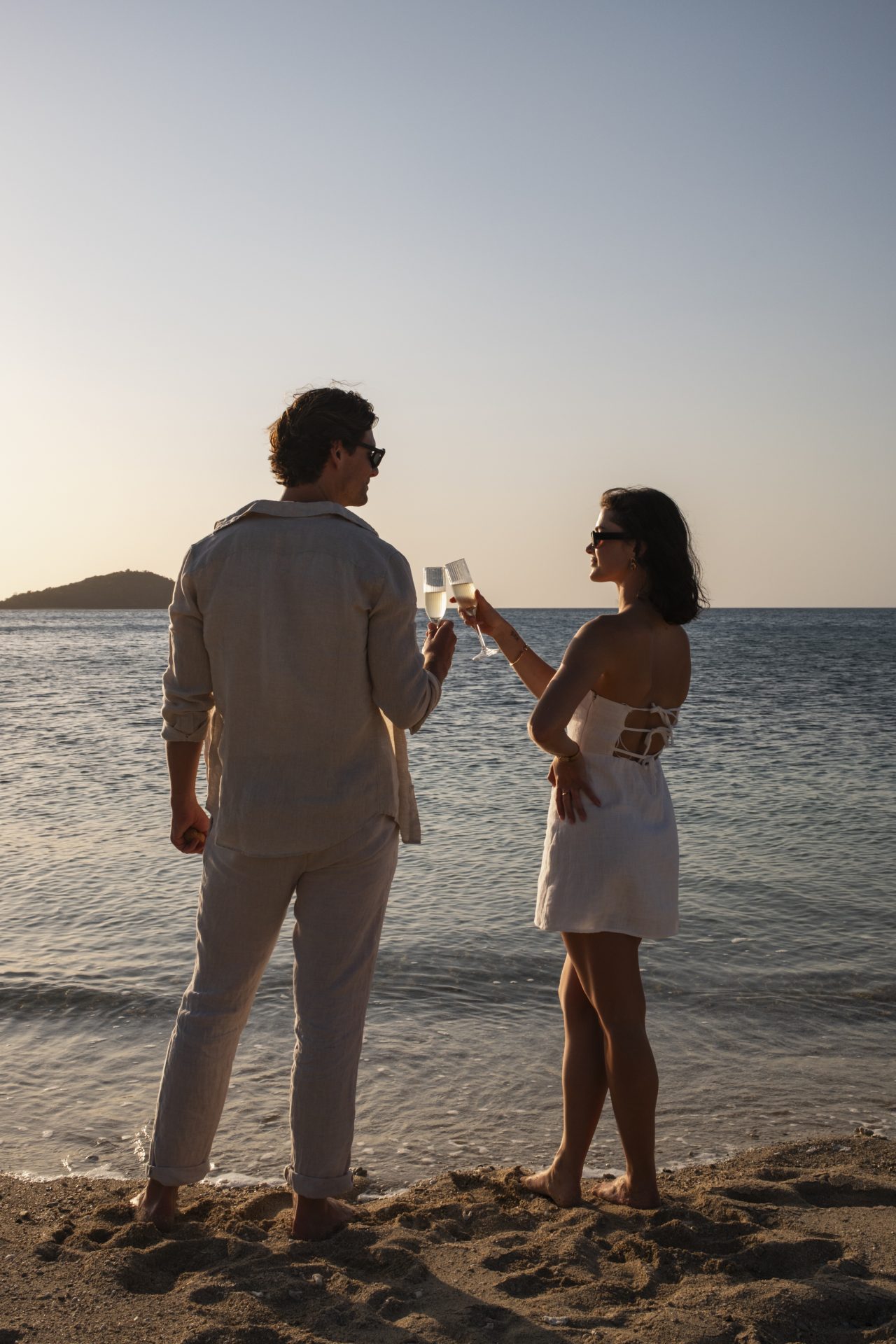 Couple watching sunset from Hayman Island beach with Whitsunday Islands in background